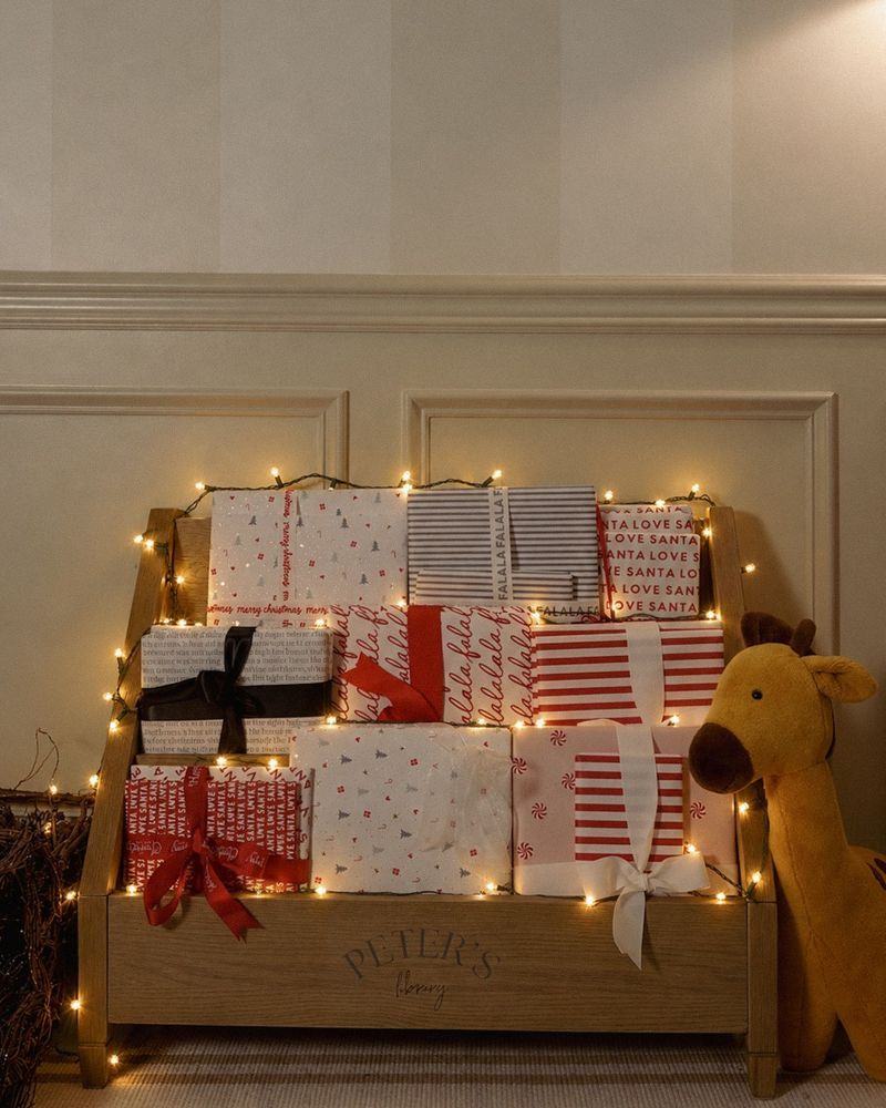 A bench stacked with wrapped, numbered books under twinkle lights