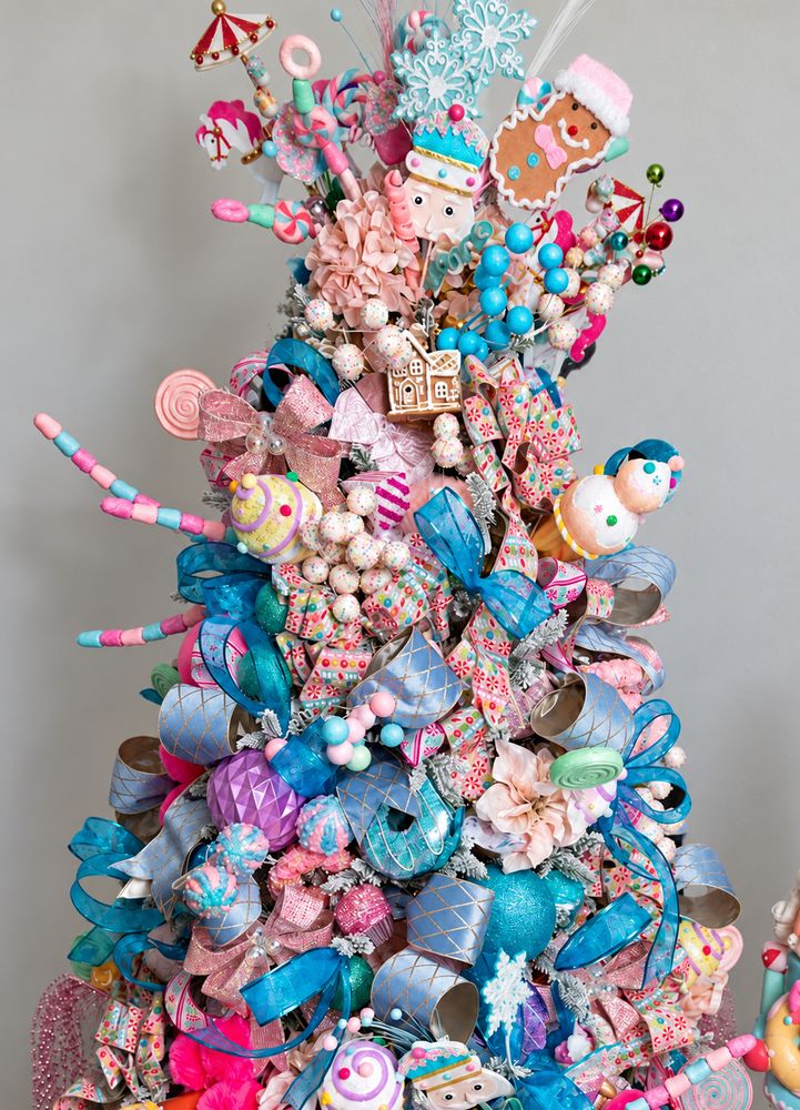 The top of a pastel candy tree: gingerbread, a nutcracker, snowflakes, lollipops and blue ribbon